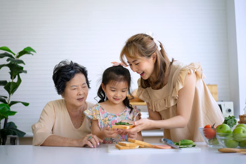 Grandmother, mother, and granddaughter preparing food together in the kitchen