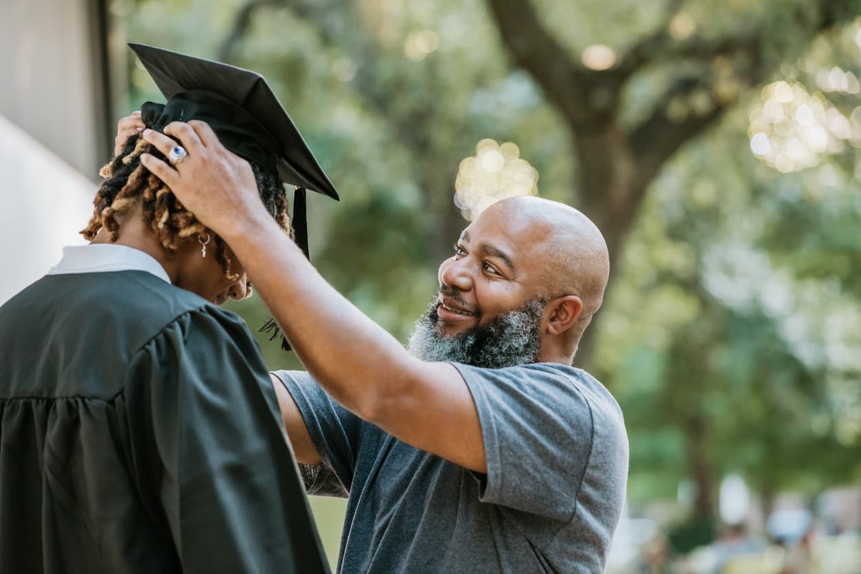 A dad helping his son with his mortarboard cap before graduation