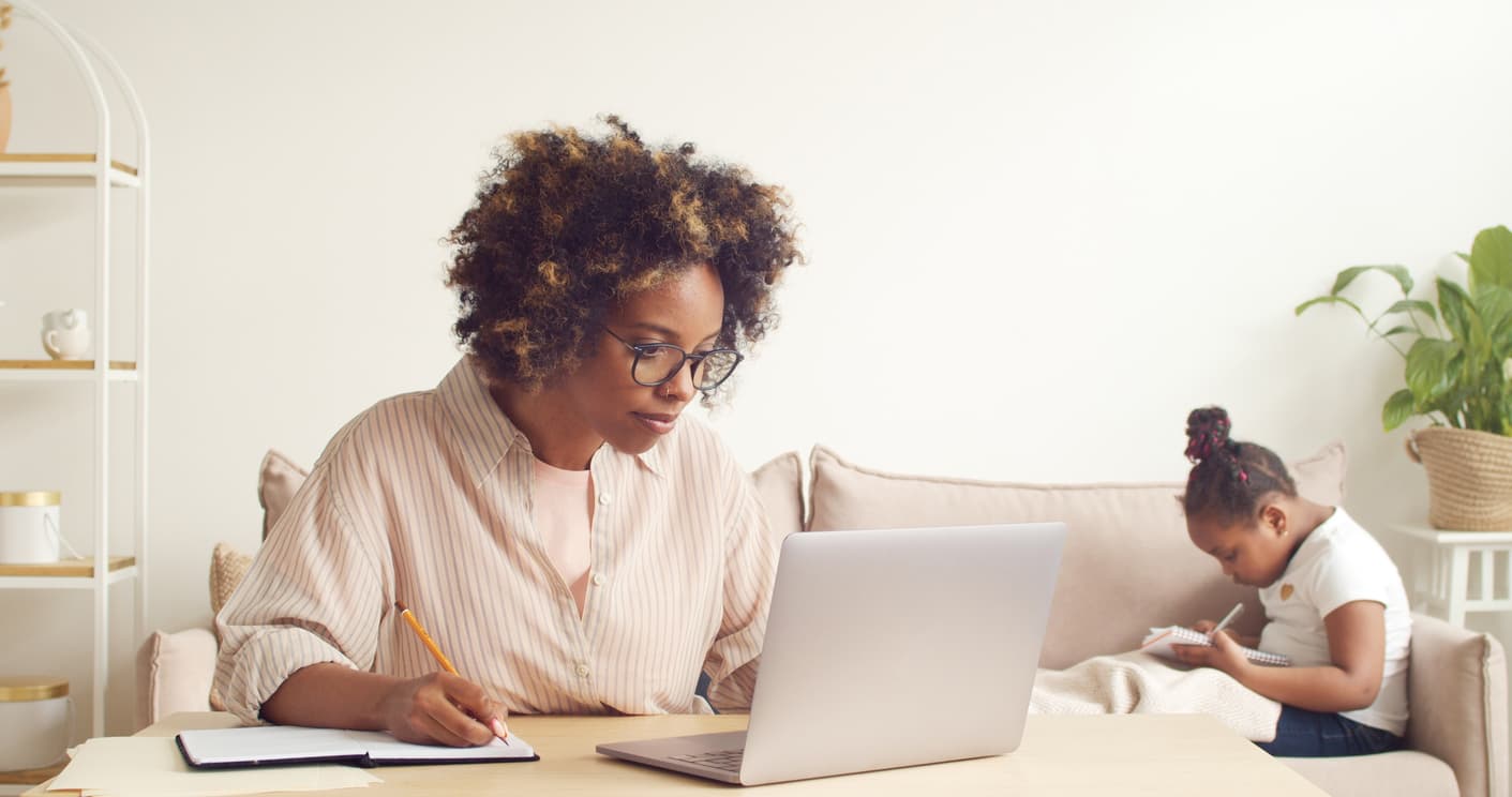 A single mom working at home online with her child on the couch